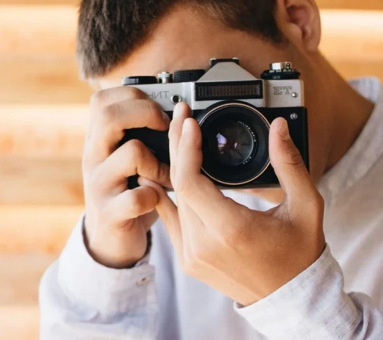 Man holding a camera and taking a photograph, representing social anxiety and fear of being observed or judged.